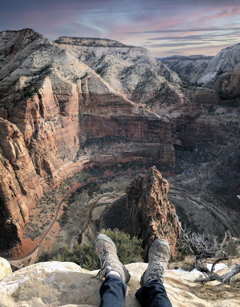 picture of person sitting on the summit of the angels landing hike zion during sunset
