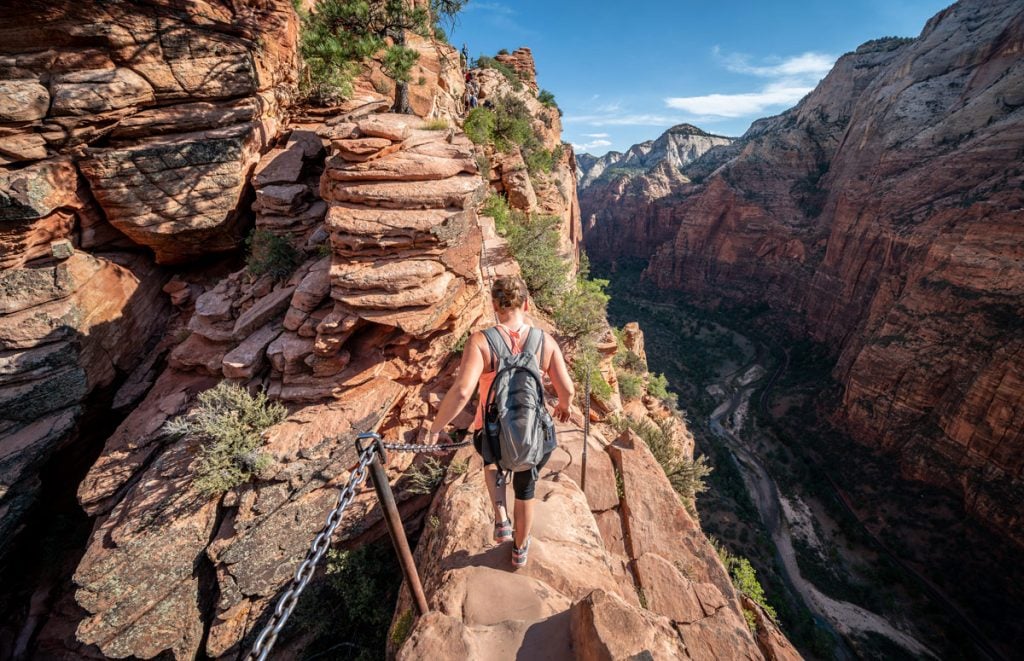 picture of hiker climbing up chains to the summit of angels landing