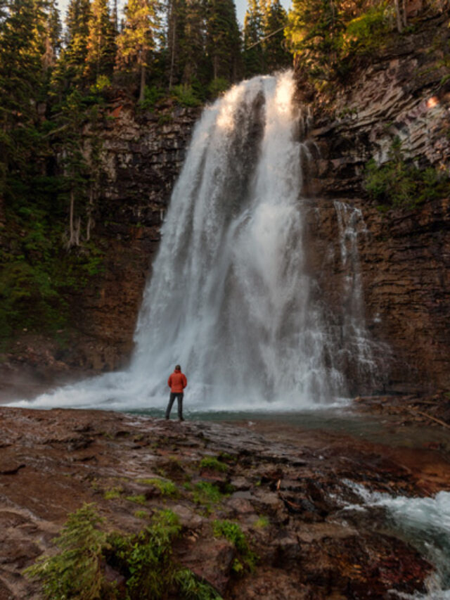 hiker standing next to virginia falls in glacier national park montana