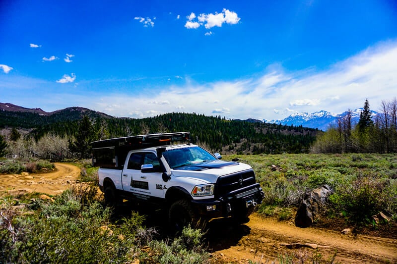 four wheel campers hawk truck camper driving down a road in the national forest