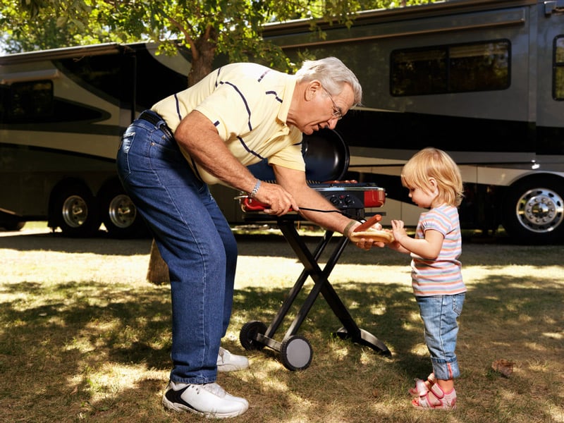 grilling a hot dog on a portable propane grill in front of an rv