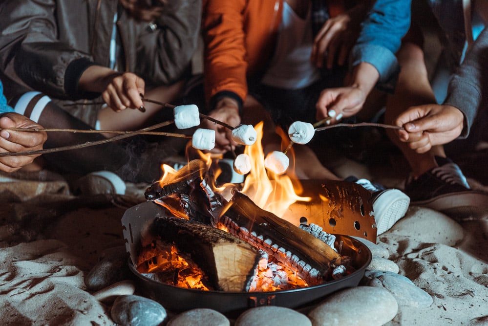 cooking smores on a campfire with a roasting stick