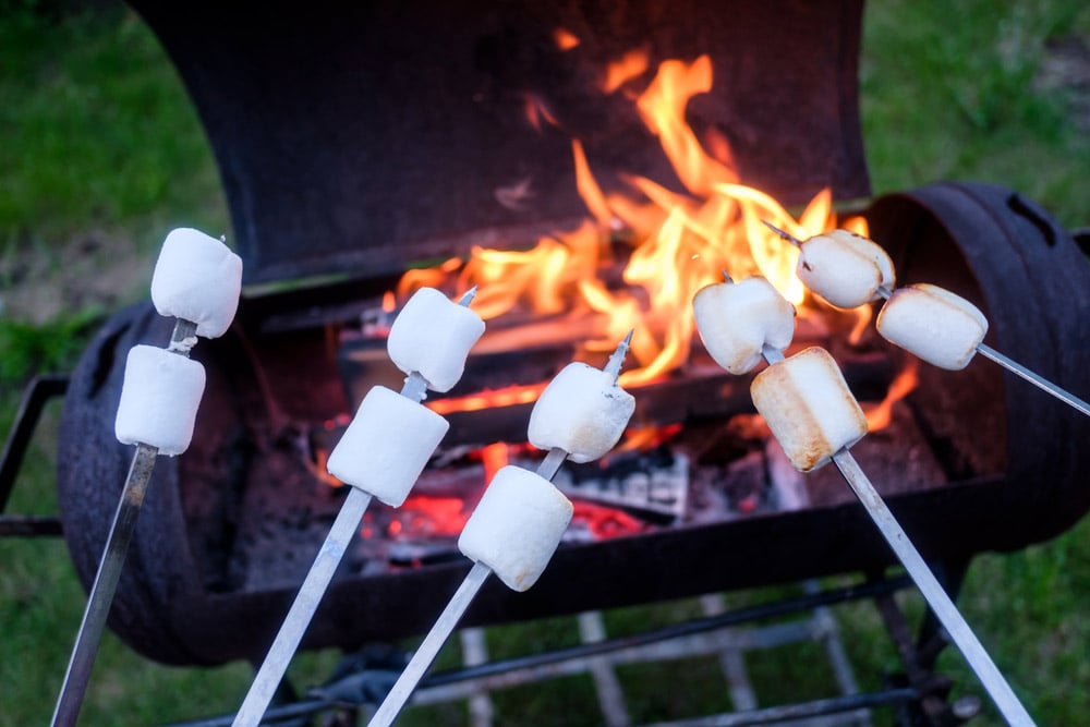 roasting marshmallows on a grill with a smores stick