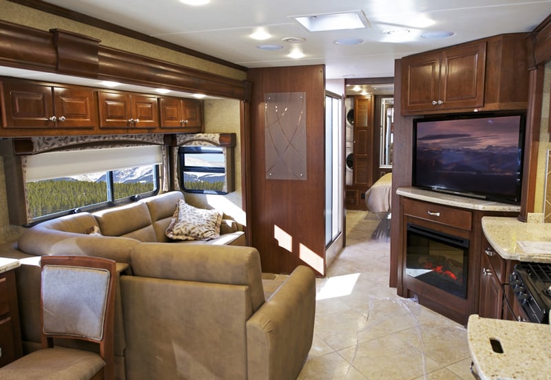 modern class A motorhome with residential features including a large living area with slides, television, and electric fireplace
