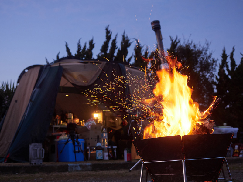 wood burning campfire next to a camping tent