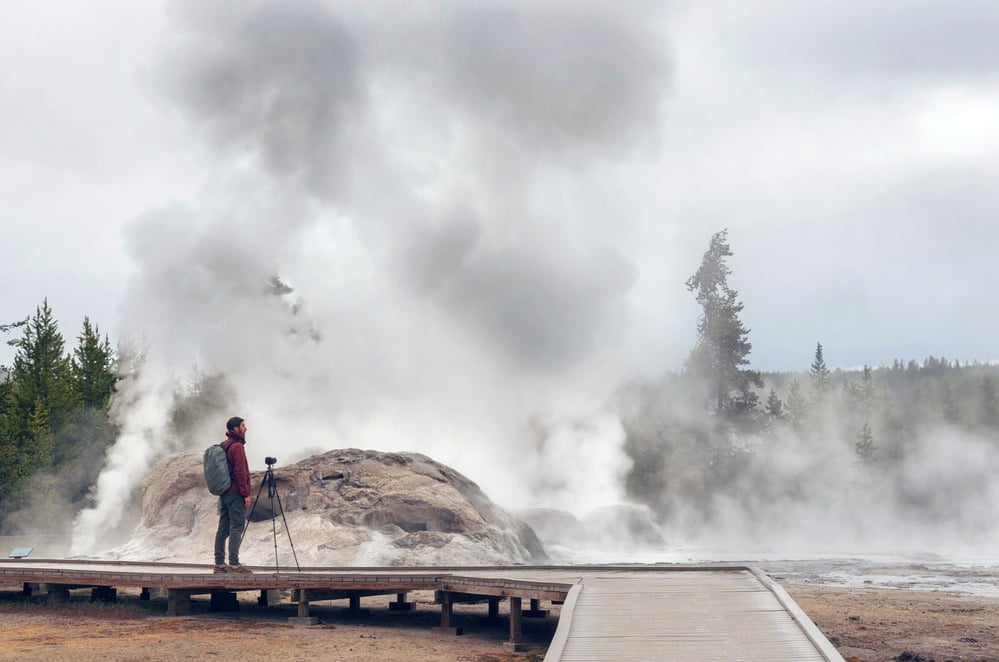 photographer taking picture of a geyser eruption and other things in yellowstone national park